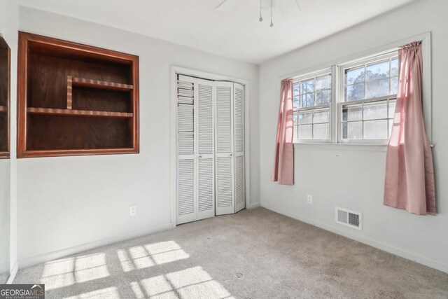 unfurnished bedroom with baseboards, visible vents, carpet, a closet, and ceiling fan