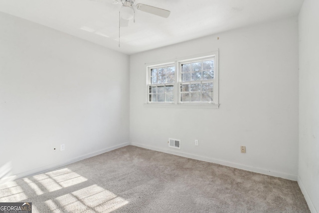 carpeted spare room with baseboards, visible vents, and ceiling fan
