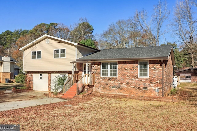 tri-level home with brick siding, roof with shingles, driveway, and crawl space
