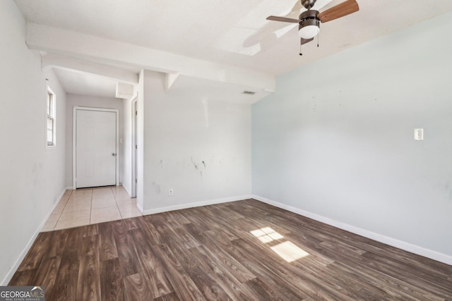 spare room featuring wood finished floors, visible vents, a ceiling fan, and baseboards