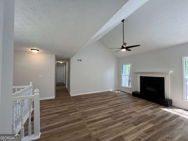unfurnished living room with wood finished floors, a textured ceiling, a ceiling fan, and baseboards