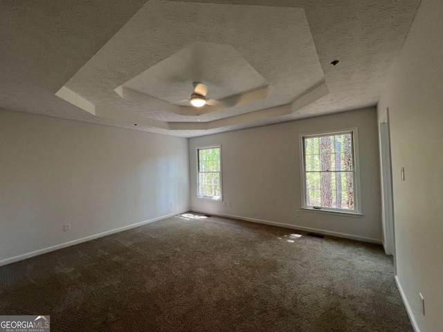 carpeted empty room featuring baseboards, a tray ceiling, and a textured ceiling
