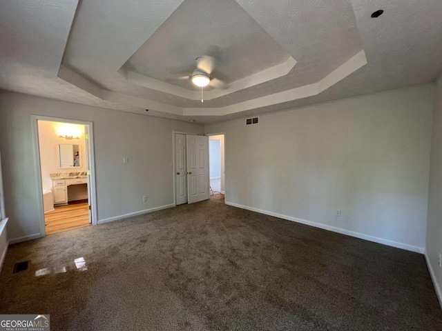 unfurnished bedroom with carpet, baseboards, visible vents, and a raised ceiling