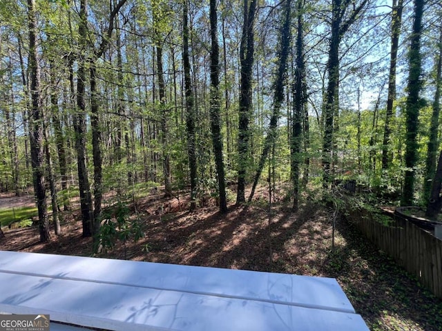 view of yard featuring a forest view and fence