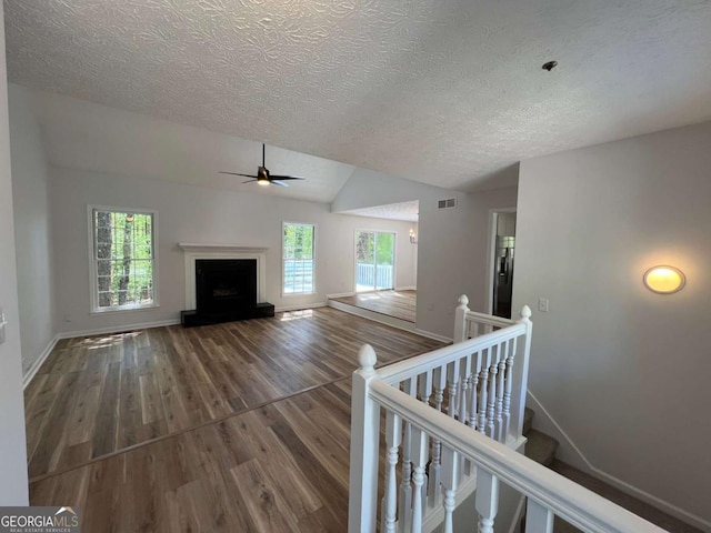 unfurnished living room with wood finished floors, a textured ceiling, a ceiling fan, and plenty of natural light