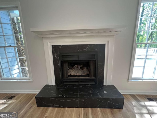 details with visible vents, baseboards, wood finished floors, and a fireplace with raised hearth