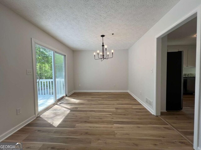 3861 Spring Meadow Dr, Acworth, GA 30101 - unfurnished dining area featuring a chandelier, a textured ceiling, and wood finished floors