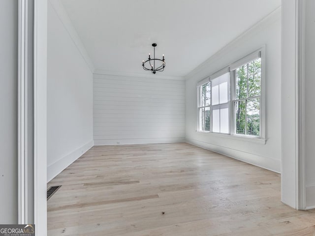 unfurnished dining area with ornamental molding, a chandelier, and wood finished floors