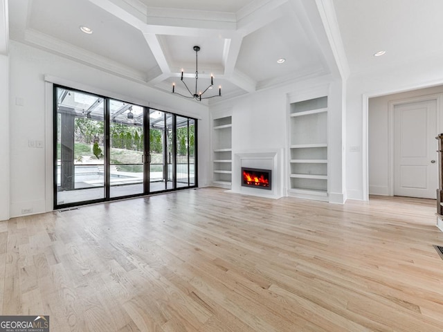 unfurnished living room with built in features, a chandelier, light wood-style flooring, coffered ceiling, and beam ceiling