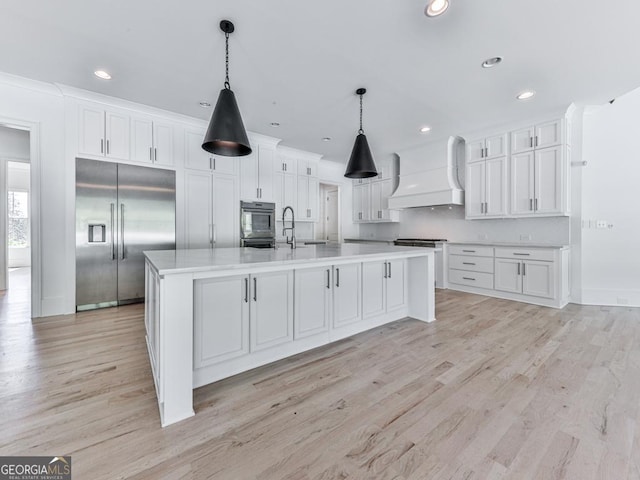 kitchen featuring stainless steel built in fridge, custom exhaust hood, white cabinetry, light wood-style floors, and recessed lighting