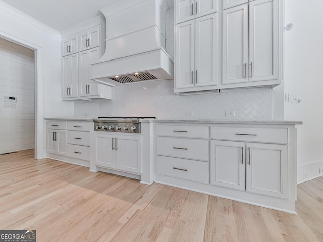 kitchen featuring custom range hood, stainless steel gas stovetop, and light wood-type flooring