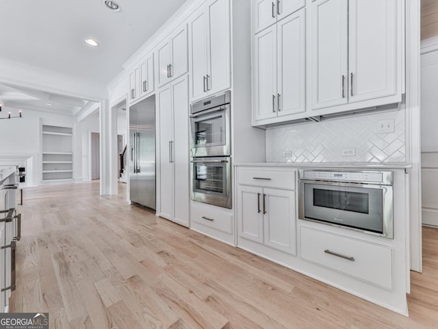 kitchen featuring stainless steel appliances, light wood-style flooring, decorative backsplash, white cabinets, and recessed lighting
