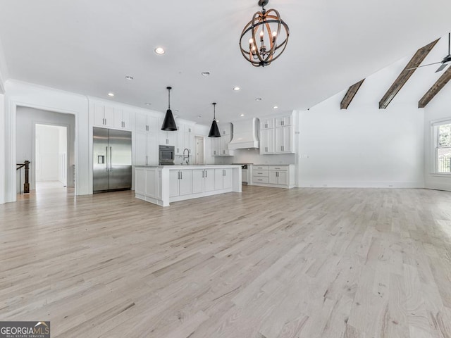 kitchen featuring built in refrigerator, open floor plan, a chandelier, premium range hood, and a sink