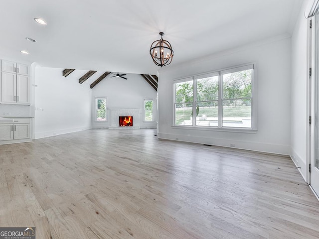 unfurnished living room with lofted ceiling, a chandelier, light wood finished floors, baseboards, and recessed lighting