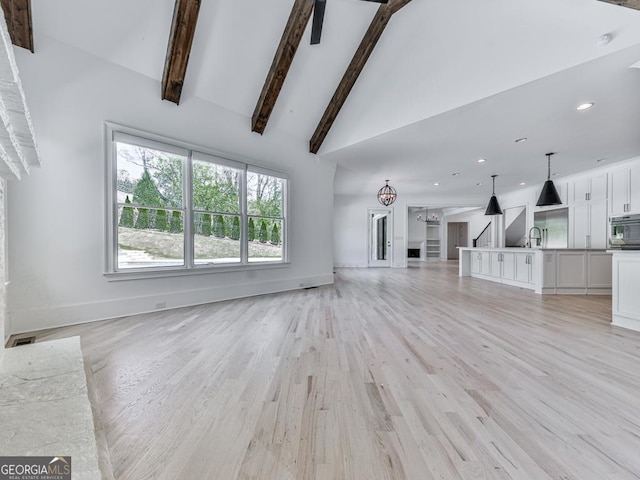 unfurnished living room featuring light wood-style flooring, baseboards, a sink, high vaulted ceiling, and recessed lighting