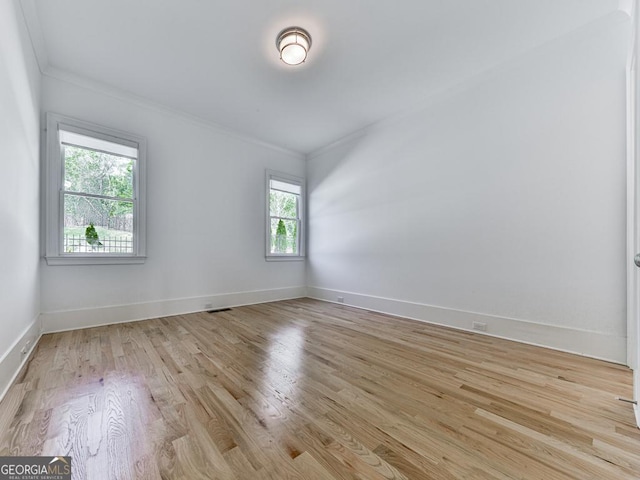 unfurnished room with crown molding, light wood-style flooring, and baseboards