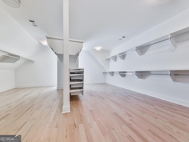 walk in closet with wood finished floors and vaulted ceiling