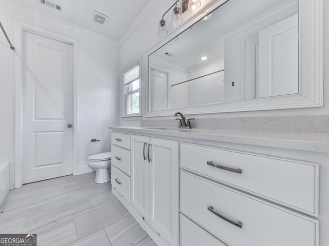 bathroom with toilet, vanity, and ornamental molding
