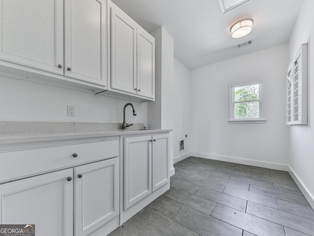 clothes washing area featuring cabinet space and baseboards