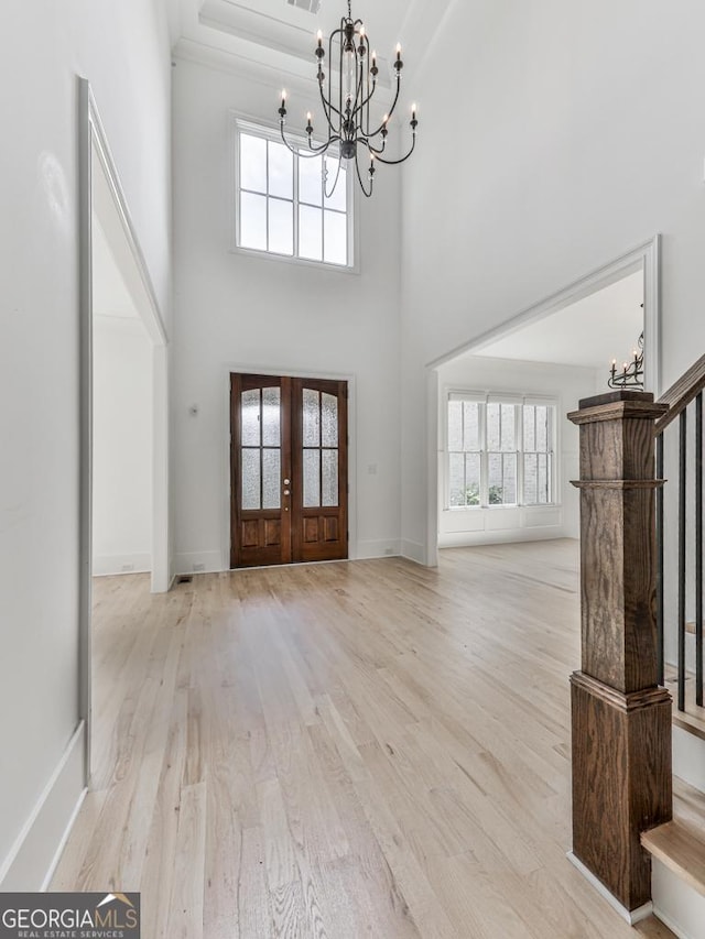 foyer entrance featuring a chandelier, stairs, wood finished floors, french doors, and a towering ceiling