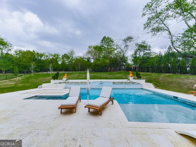 swimming pool with an in-ground hot tub, view of scattered trees, and a patio area