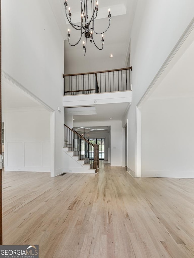 entrance foyer with a high ceiling, stairway, wood finished floors, and a chandelier