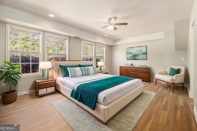 bedroom featuring baseboards, a ceiling fan, visible vents, and light wood-style flooring