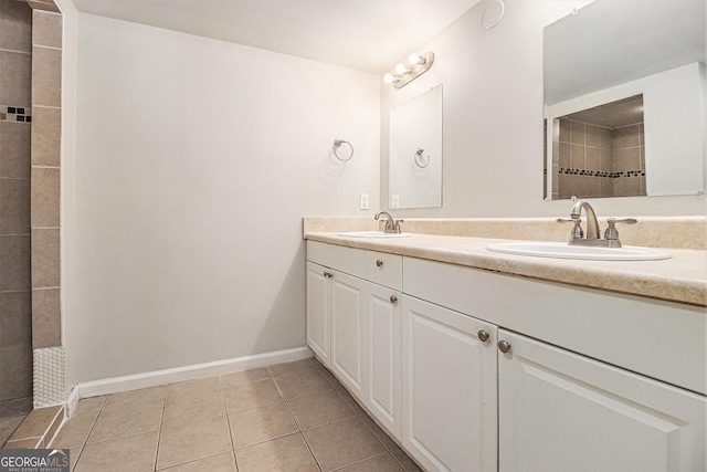 bathroom with tile patterned floors, a sink, double vanity, and a tile shower