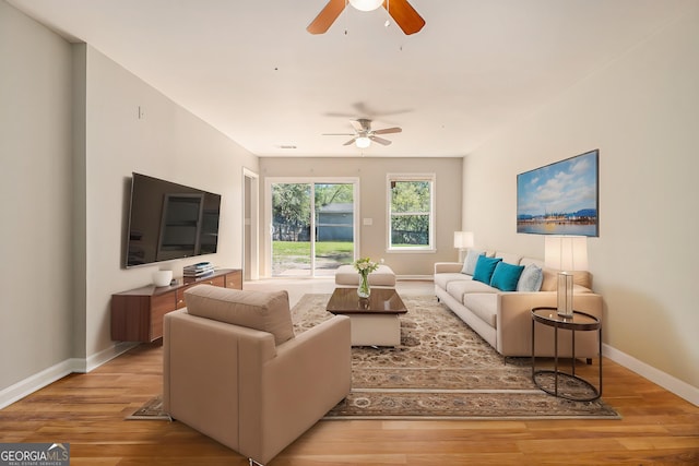living room featuring ceiling fan, baseboards, and wood finished floors