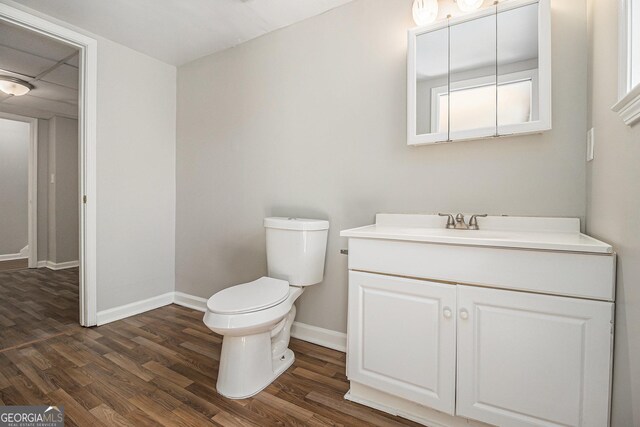 half bath with wood finished floors, baseboards, and toilet
