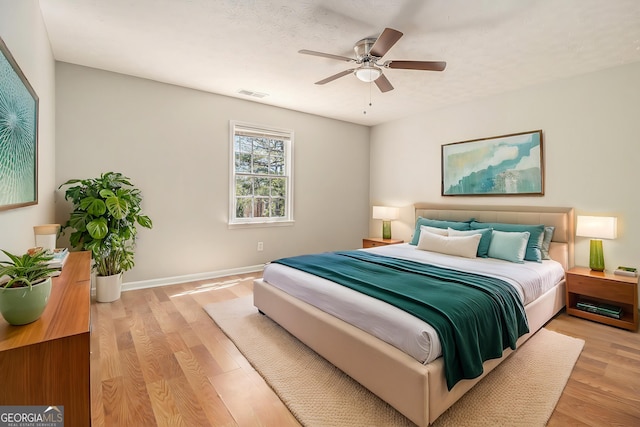 bedroom featuring a ceiling fan, baseboards, visible vents, and light wood finished floors