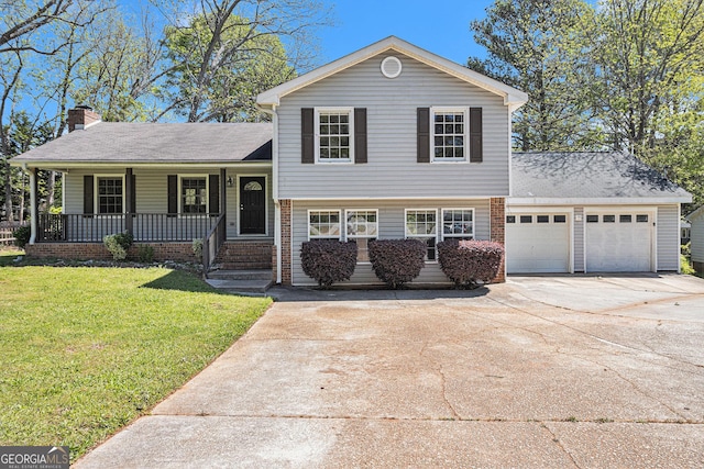 tri-level home with a chimney, concrete driveway, covered porch, a front yard, and a garage