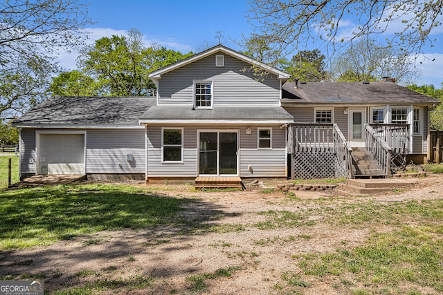 back of property featuring a garage, a yard, and a deck