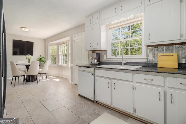 kitchen featuring dark countertops, dishwasher, decorative backsplash, and a sink