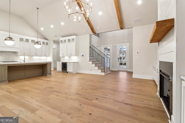 117 Wildwood Dr, Eatonton, GA 31024 - unfurnished living room featuring stairway, light wood finished floors, visible vents, a fireplace, and high vaulted ceiling