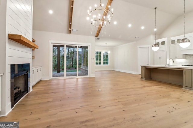 117 Wildwood Dr, Eatonton, GA 31024 - unfurnished living room with a sink, a fireplace, light wood-style flooring, high vaulted ceiling, and a notable chandelier