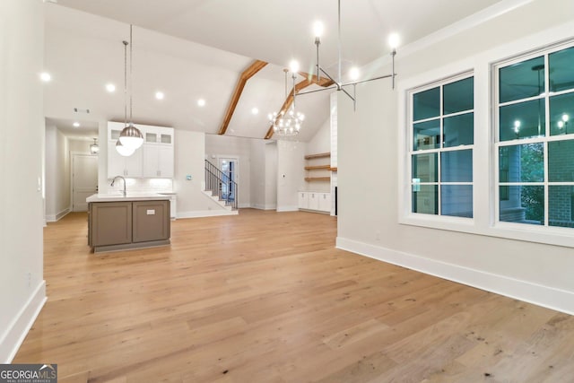 117 Wildwood Dr, Eatonton, GA 31024 - unfurnished dining area featuring high vaulted ceiling, stairs, a sink, a chandelier, and baseboards