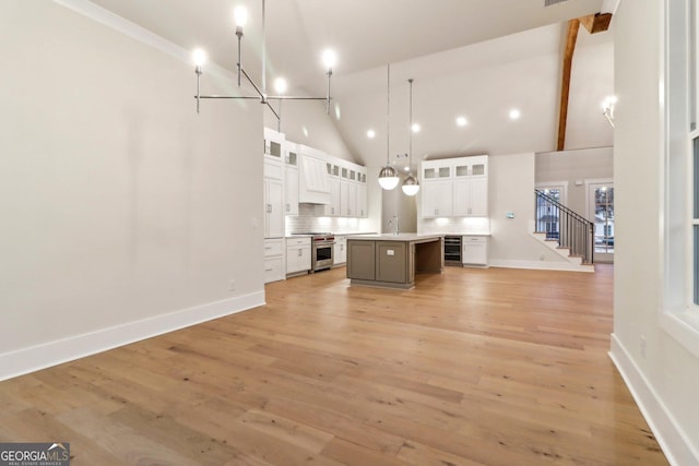 117 Wildwood Dr, Eatonton, GA 31024 - kitchen with white cabinets, an island with sink, high vaulted ceiling, high end range, and open floor plan