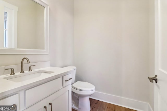 117 Wildwood Dr, Eatonton, GA 31024 - half bath with wood finished floors, vanity, toilet, and baseboards