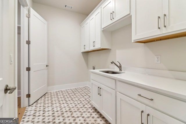 117 Wildwood Dr, Eatonton, GA 31024 - laundry room featuring light floors, baseboards, a sink, and cabinet space