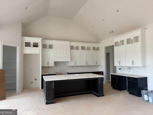 117 Wildwood Dr, Eatonton, GA 31024 - kitchen featuring dark cabinets, a kitchen island, white cabinetry, and high vaulted ceiling