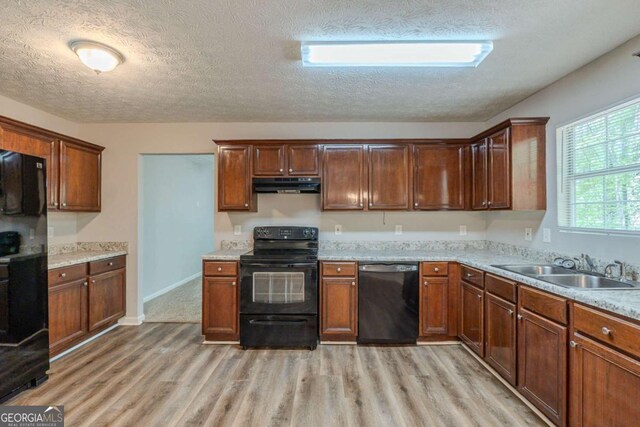 6205 Leverett Dr, Lithonia, GA 30038 - kitchen with black appliances, under cabinet range hood, light wood-style floors, a textured ceiling, and light countertops