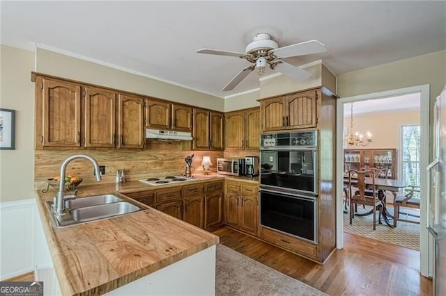5251 Amberbrook Ct, Marietta, GA 30068 - kitchen featuring dobule oven black, a sink, brown cabinetry, white cooktop, and under cabinet range hood