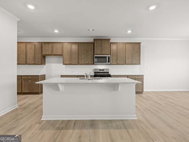 131 Hampton Ter, Dallas, GA 30157 - kitchen featuring a sink, light wood-style flooring, a kitchen island with sink, tasteful backsplash, and appliances with stainless steel finishes