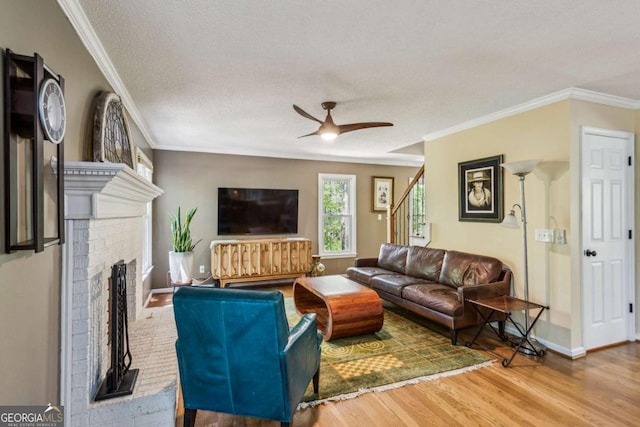 5876 Bridgemont Pl NW, Acworth, GA 30101 - living area featuring a textured ceiling, a ceiling fan, wood finished floors, a fireplace, and ornamental molding