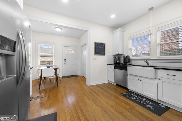 kitchen featuring dark countertops, plenty of natural light, white cabinetry, and stainless steel appliances