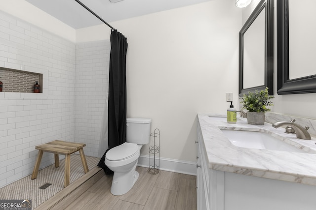full bathroom featuring tiled shower, toilet, baseboards, vanity, and wood finish floors