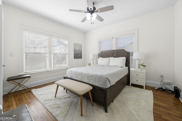 bedroom featuring hardwood / wood-style floors, a ceiling fan, baseboards, and multiple windows