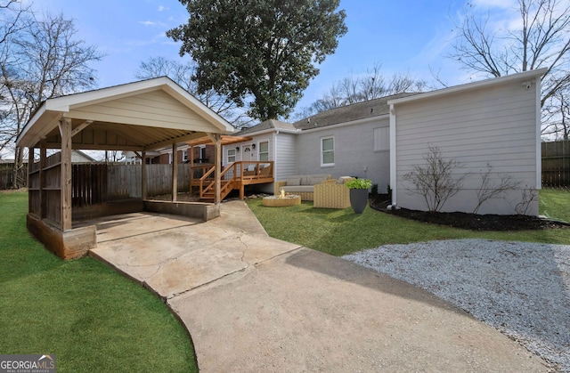 back of property featuring a yard, a carport, fence, and a deck