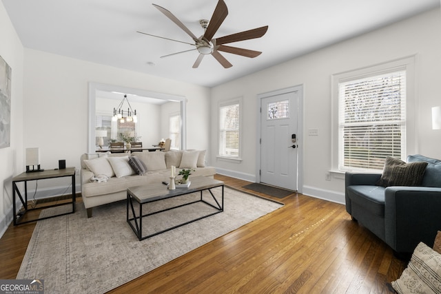 living area with hardwood / wood-style flooring, baseboards, and ceiling fan with notable chandelier